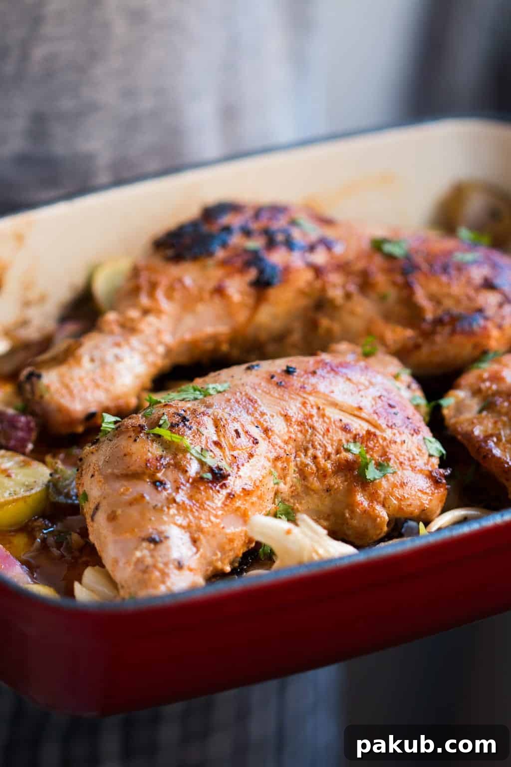 A portion of Sumac Chicken with caramelized onions and garlic sumac chicken in a red pan