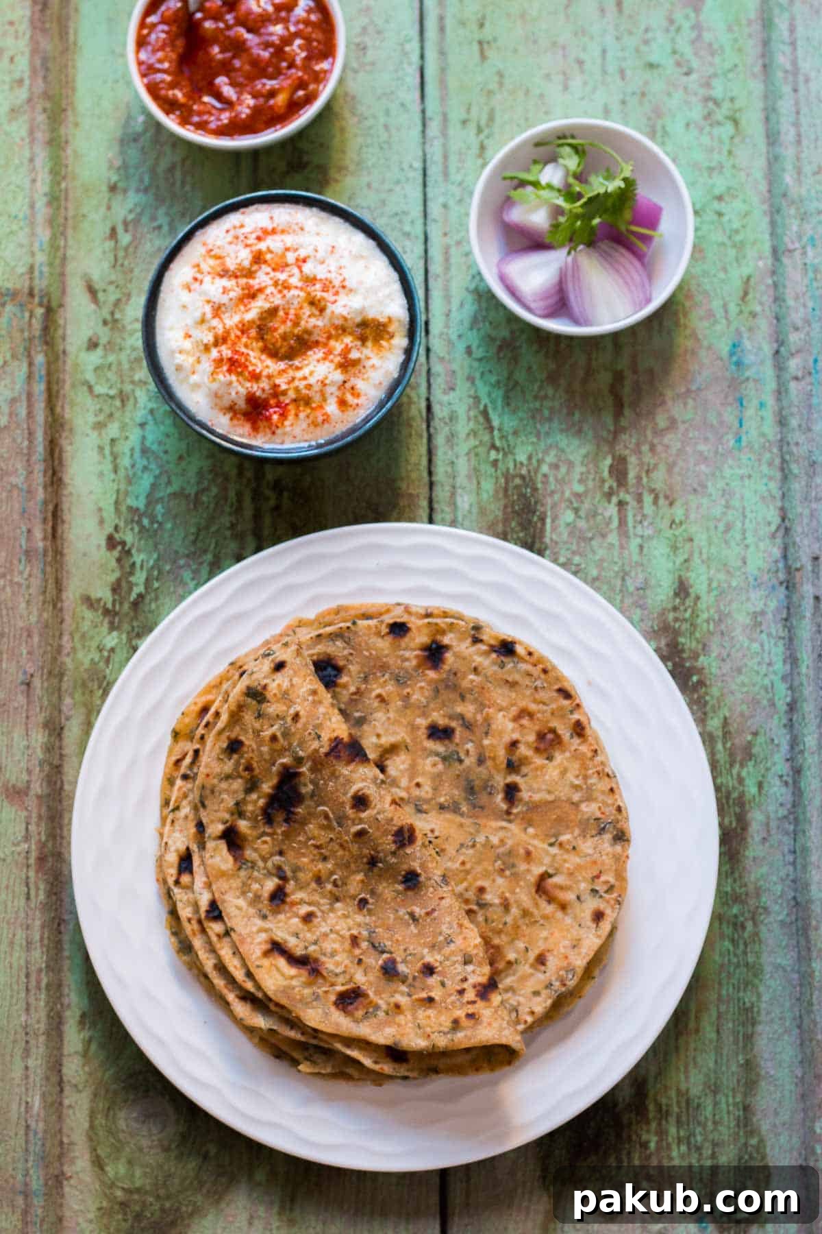 Aromatic Kasuri Methi Flatbread 6 A vibrant platter of Kasuri Methi Parathas served with a medley of flavored curds, fresh onions, and a traditional Indian pickle.