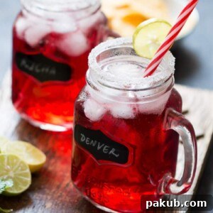 Cranberry Ginger Holiday Cocktail served in mason jars with sugar coated rims and a slice of lime.