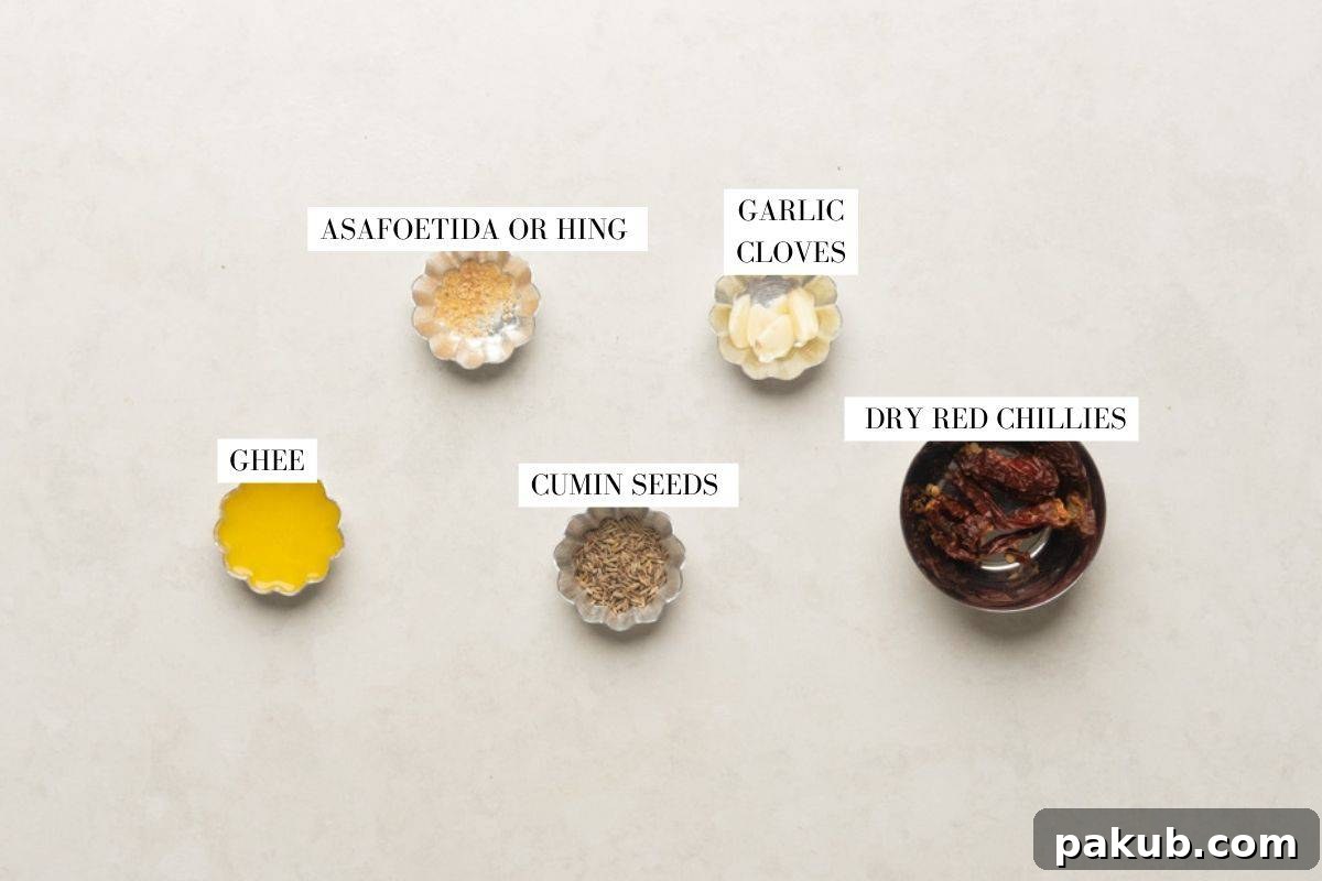 Picture of ingredients for tempering Palak Paneer Kofta Curry, including ghee, asafoetida, cumin seeds, garlic, and dry red chilies.