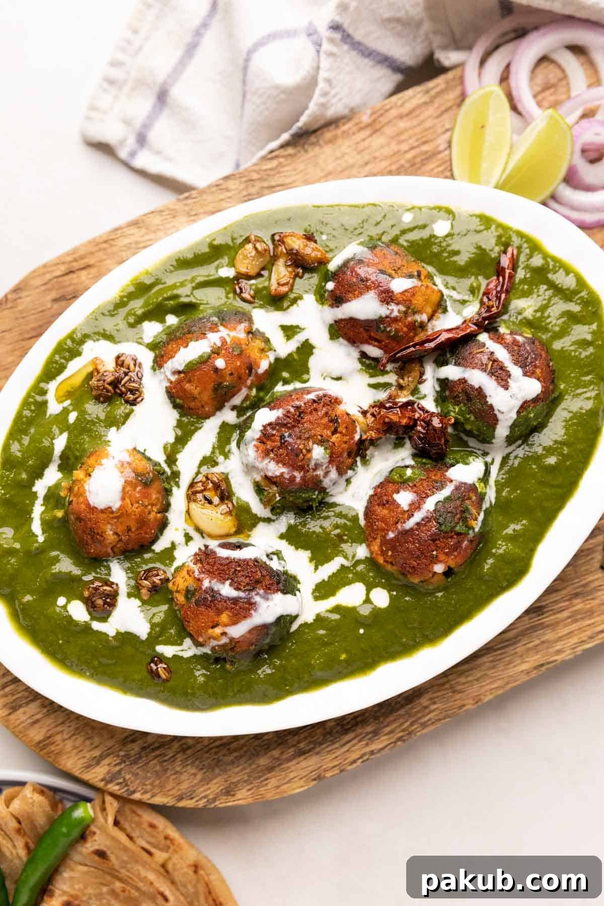 The Healthy Palak Paneer Kofta Curry in a dish with cream drizzled on top, ready to serve.