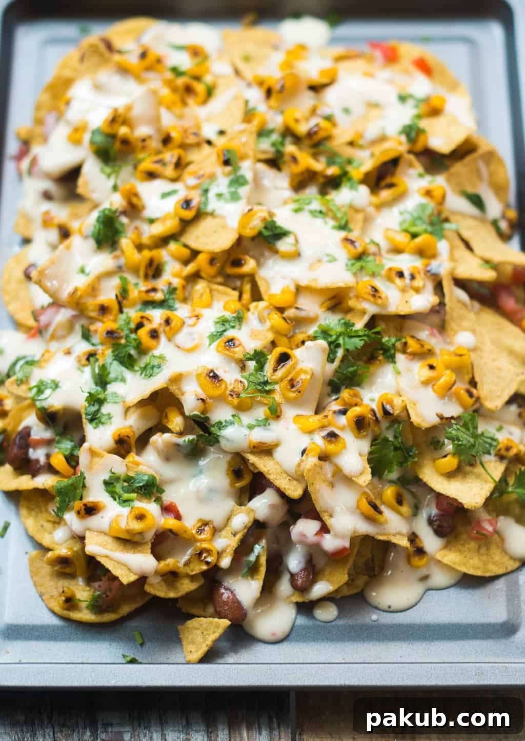Loaded Nachos for Sharing A beautifully arranged platter of loaded nachos with all toppings, garnished with fresh cilantro, ready for serving.