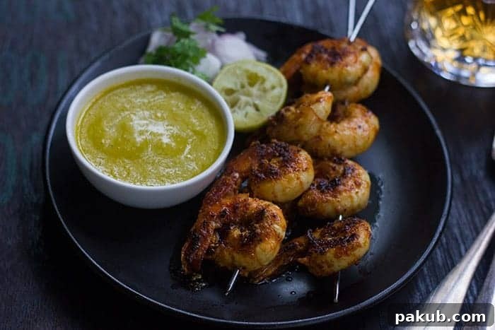 The Best Tandoori Prawns Recipe Vibrant Tandoori prawns served with tangy mango chutney, fresh lemon wedges, thinly sliced onions, and a sprinkle of coriander.
