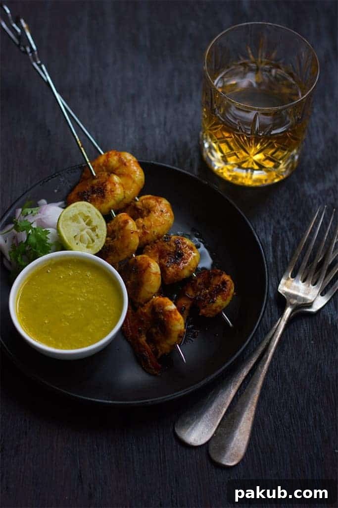 Serving Tandoori Prawns with Chutney A beautifully presented plate of Tandoori prawns, garnished with fresh coriander and served with a vibrant mango chutney, lemon wedges, and sliced red onions.