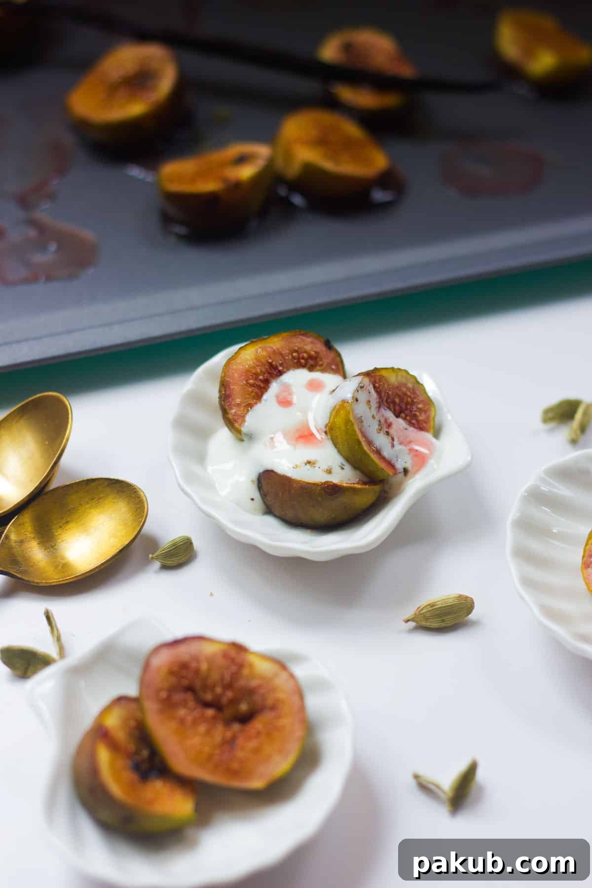 Multiple small white bowls are perfectly arranged, each filled with beautifully roasted figs and creamy cardamom yogurt, prepared for an elegant serving.