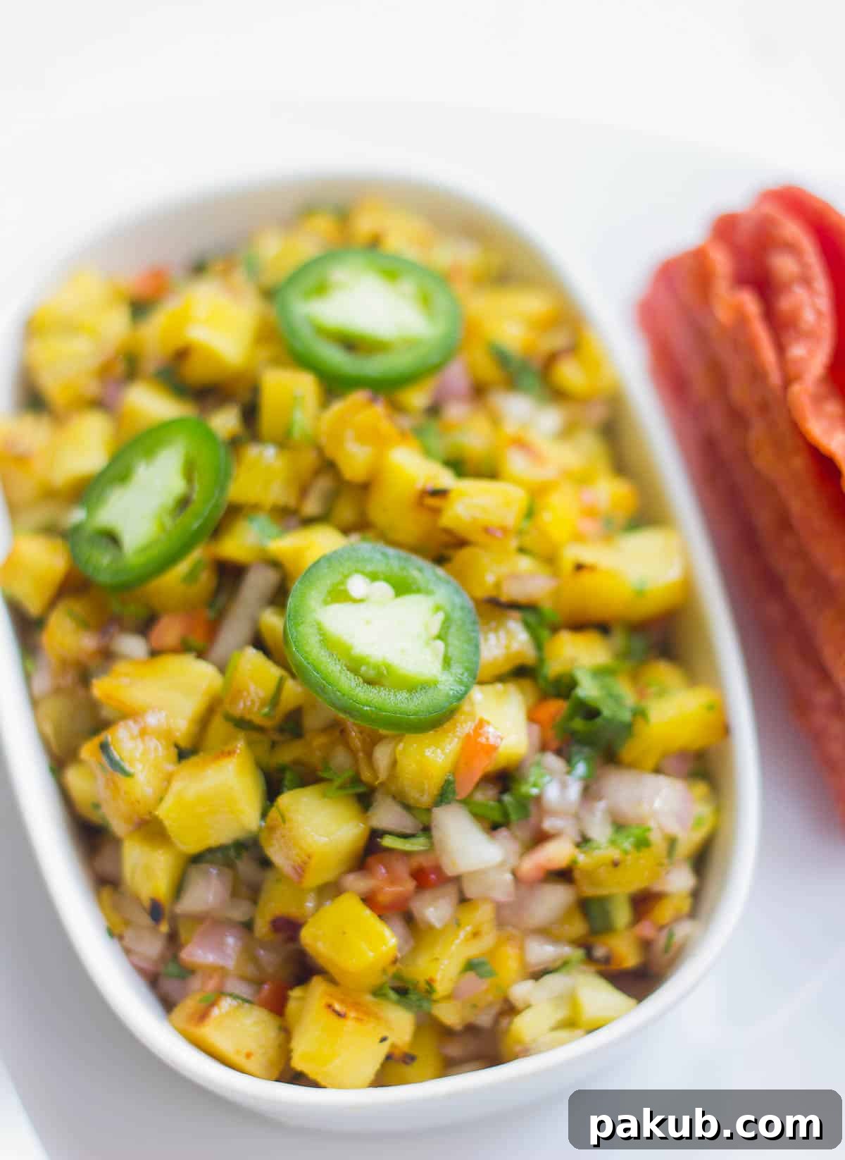 Grilled Pineapple Habanero Salsa 4 Close-up of Spicy Grilled Pineapple Salsa in a white dish, garnished with fresh jalapeño and cilantro.