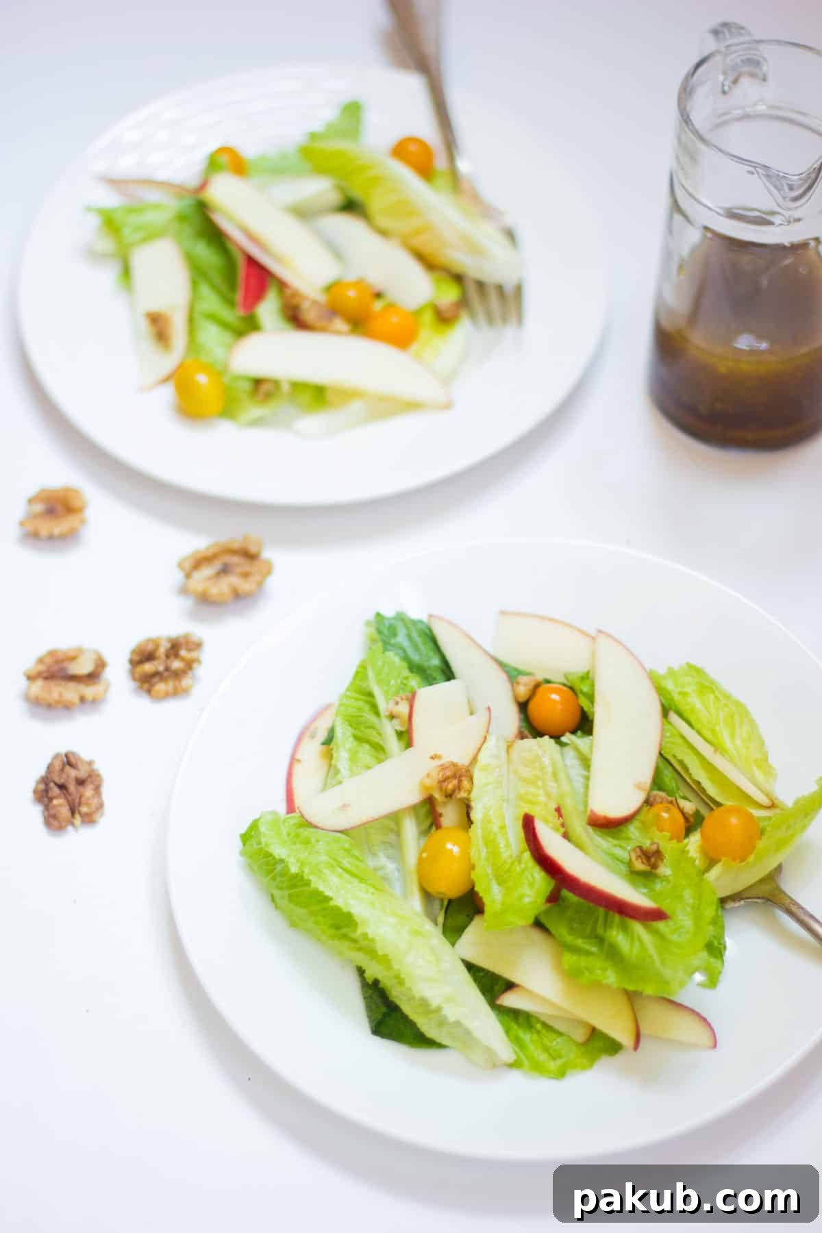 Refreshing Summer Apple Walnut Delight 2 Two white bowls filled with a vibrant Apple Walnut Summer Salad, garnished with fresh herbs, showcasing sliced apples, walnuts, and lettuce.