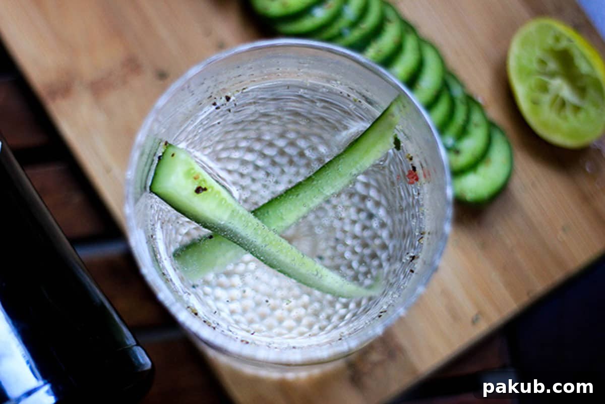 A vibrant, top-down shot of a Sparkling Cucumber Chili Gin cocktail in a glass, garnished with cucumber slices.