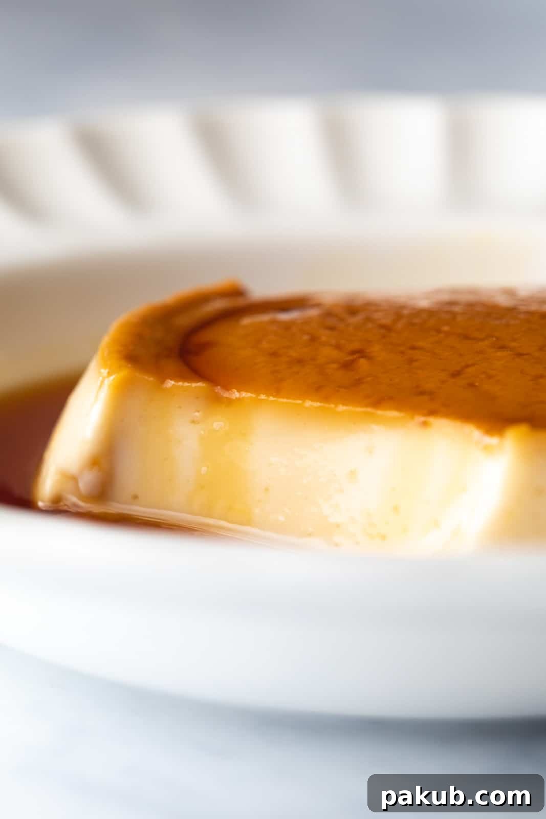 Closeup of the perfectly set, smooth texture of coconut caramel custard after taking a bite, showing its rich consistency.