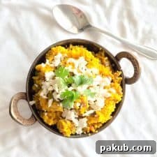 A picture of Comforting Bulgur Wheat Daliya garnished with cottage cheese and coriander and served against a white background.