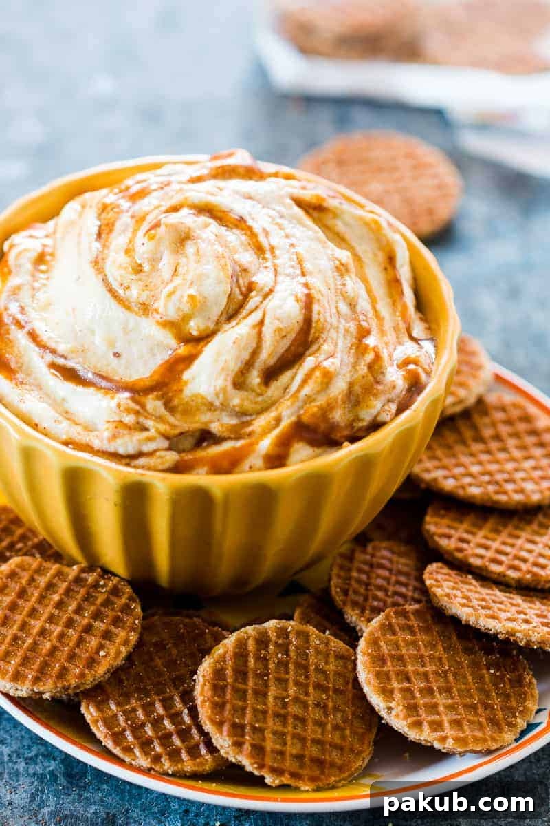 A beautifully presented Caramel Pumpkin Pie Cheesecake Dip, garnished and surrounded by graham crackers and waffle bites, set against a cozy fall backdrop.