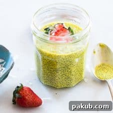 Golden Turmeric Milk Chia Seed Pudding topped with strawberries and served in a glass jar.