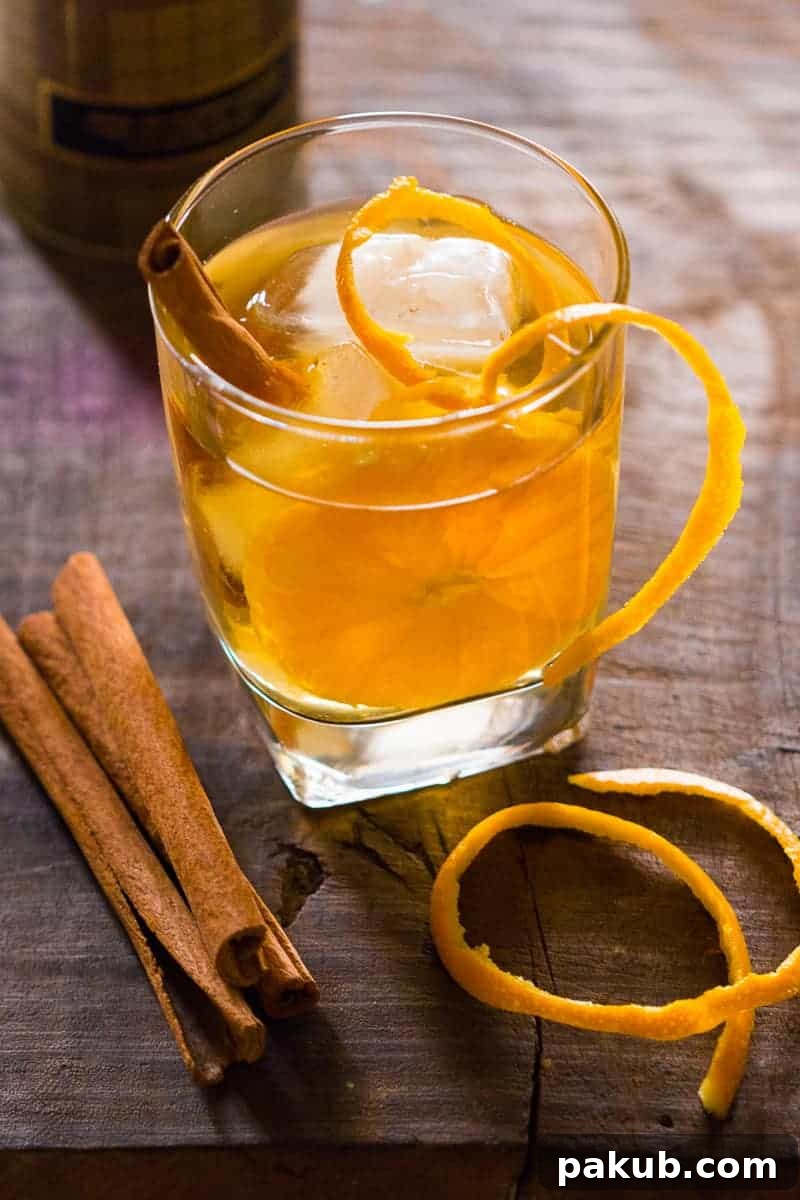 The final presentation of the Orange Cinnamon Whisky Smash, glistening with ice and orange slices.