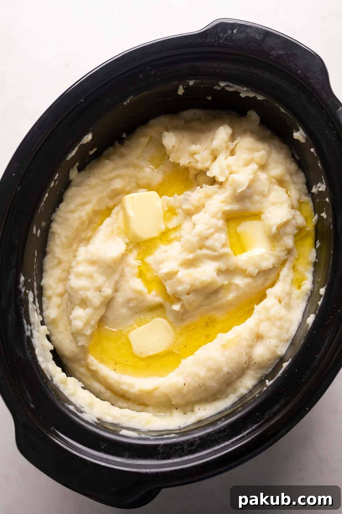 Mashed potatoes cooked and served in the slow cooker with blobs of butter on top