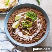 Dal Makhani topped with cream, coriander, ginger, lime and served in a blue bowl.