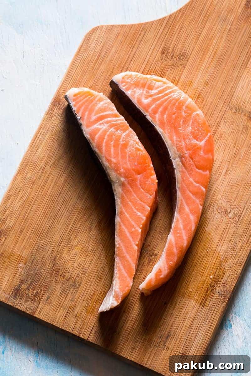 Sizzling Salmon with Orange-Mustard Glaze 3 Close-up of three salmon fillets in a cast iron pan, coated with a luscious, bubbling orange mustard glaze, ready to absorb all the flavors.