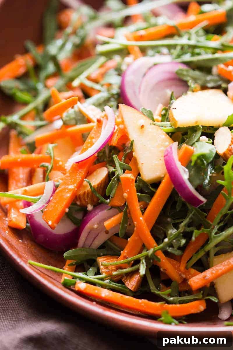 Sunshine Citrus Arugula Salad with Apples and Almonds 4 A fresh Apple Arugula Almond Salad with Orange Marmalade Dressing in a rustic wooden bowl, with ingredients scattered around, emphasizing its natural and healthy appeal. This quick and easy recipe is perfect for vegan and gluten-free diets, serving as an ideal healthy side dish or light meal.