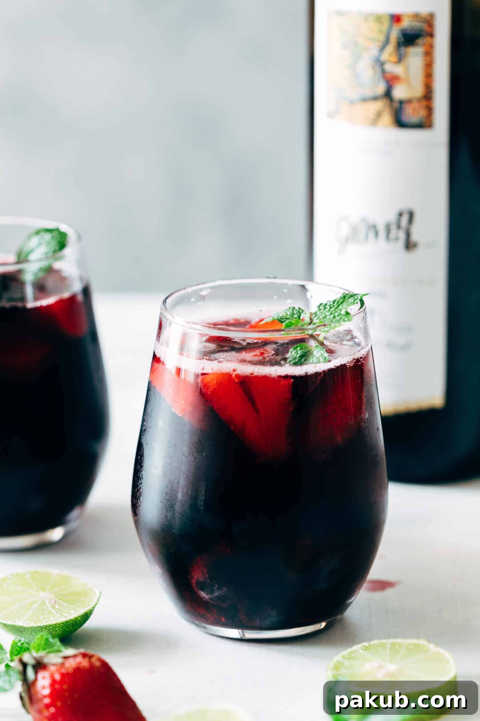 A vibrant Summer Berry Red Wine Spritzer cocktail, garnished with fresh berries and mint, presented in a elegant glass.