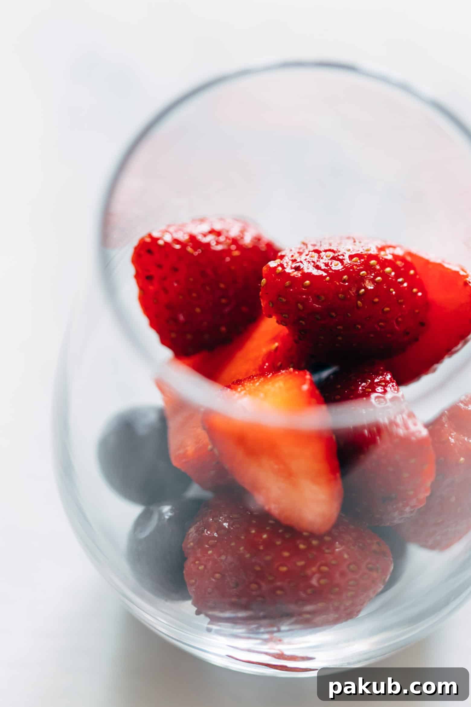A glass of Summer Berry Red Wine Spritzer with a focus on fresh blueberries, highlighting the refreshing fruit components.