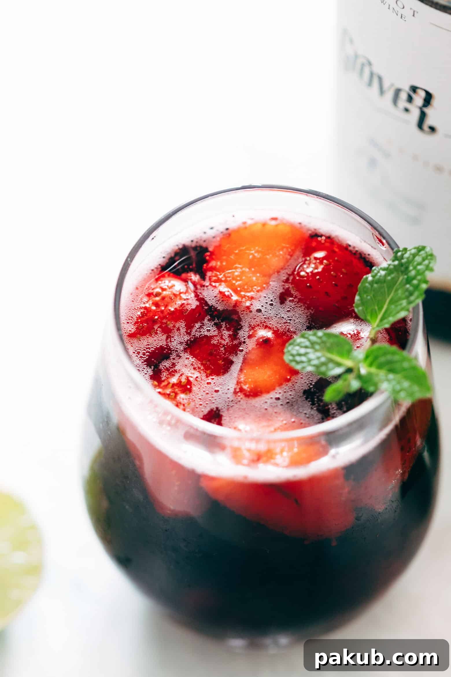 A close-up of a Summer Berry Red Wine Spritzer, garnished with fresh mint, showing the beautiful presentation.