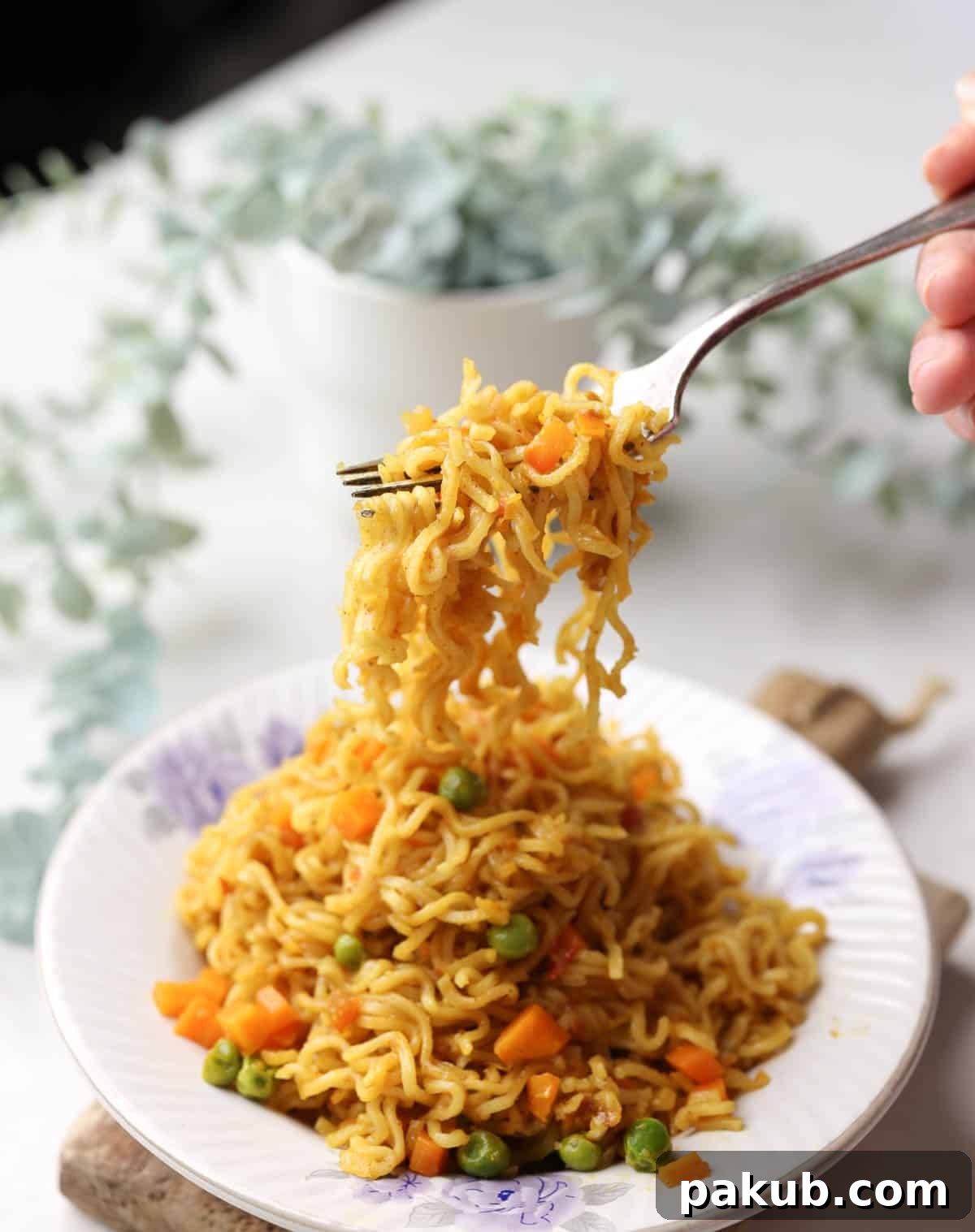 A plate of hot and spicy Masala Maggi noodles, garnished with fresh coriander, with a fork ready to pick up a delicious bite.