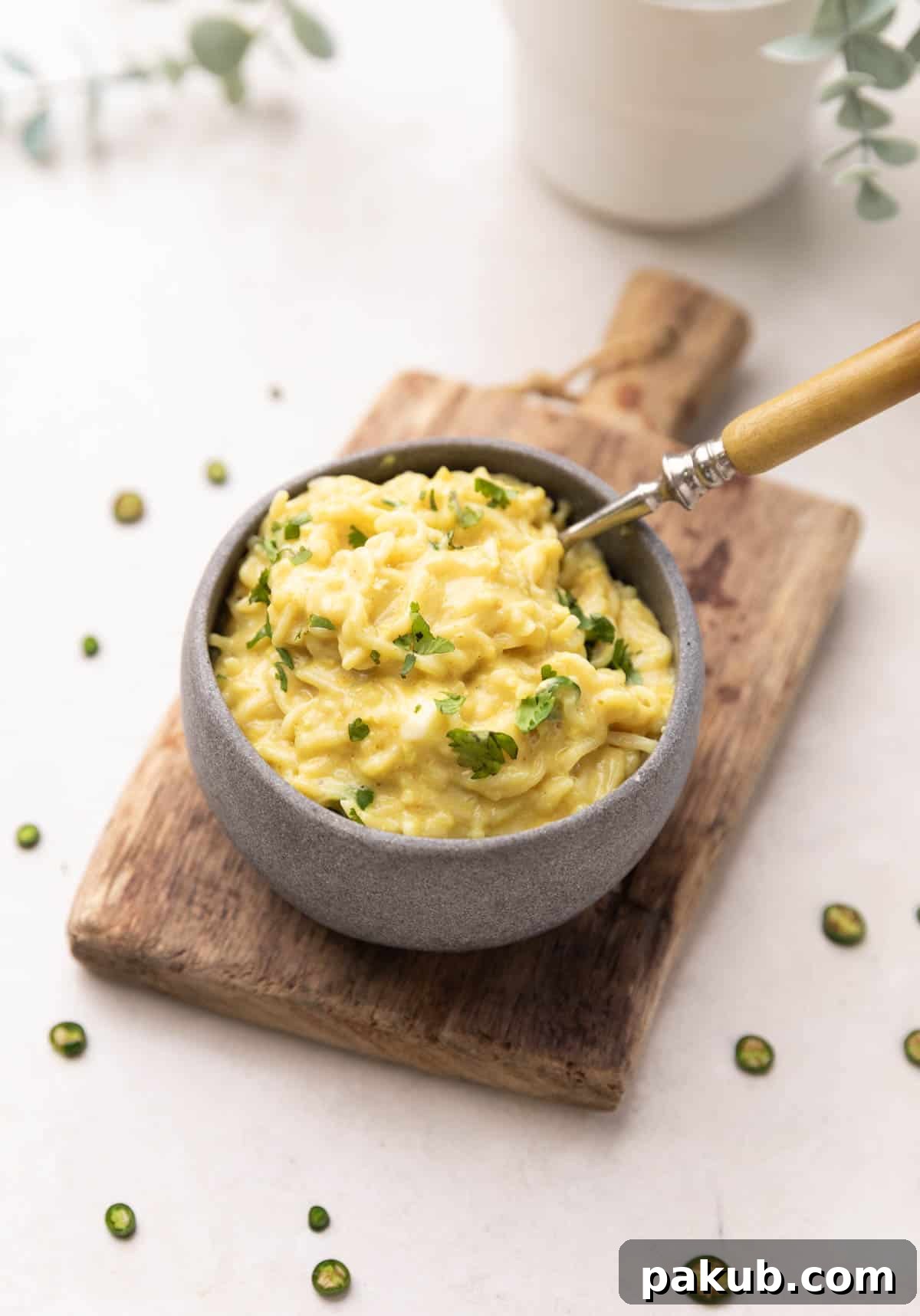 A comforting bowl of Cheese and Egg Maggi noodles, with visible scrambled egg pieces and melted cheese, served on a rustic brown board with a fork.