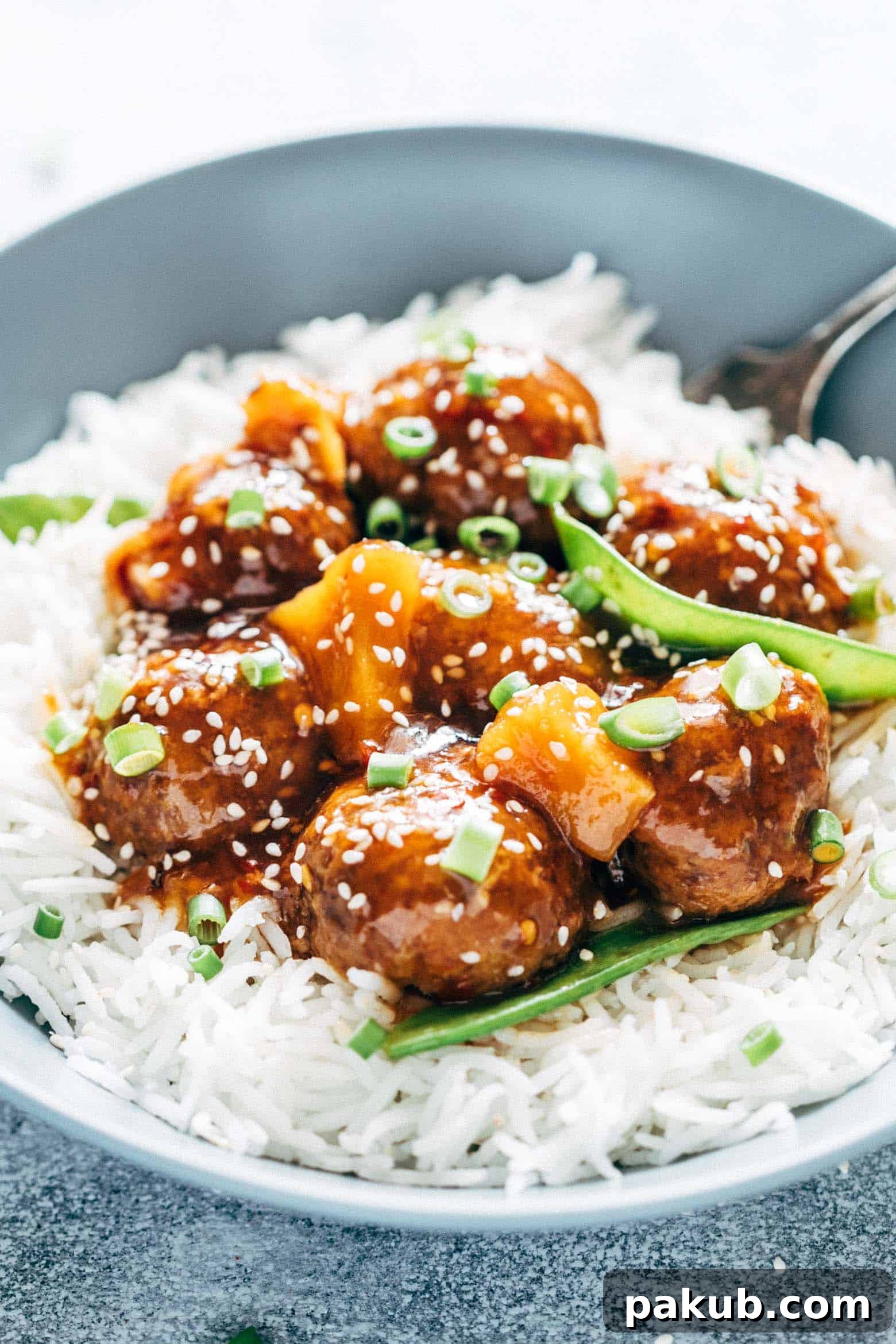 A closer look at the Slow Cooker Teriyaki Meatballs with Pineapple, showing the succulent meatballs drenched in sauce alongside juicy pineapple chunks, garnished with sesame seeds and green onions.