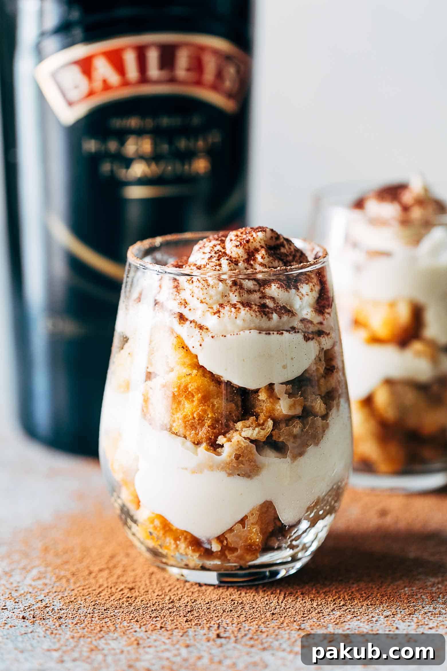 Individual Baileys Tiramisu Trifle Cups, layered with coffee-soaked ladyfingers and creamy mascarpone, topped with cocoa powder, inviting a delicious experience.