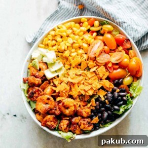 Zesty Shrimp Avocado Taco Bowl 8 Ingredients of the salad assembled together in a white bowl.