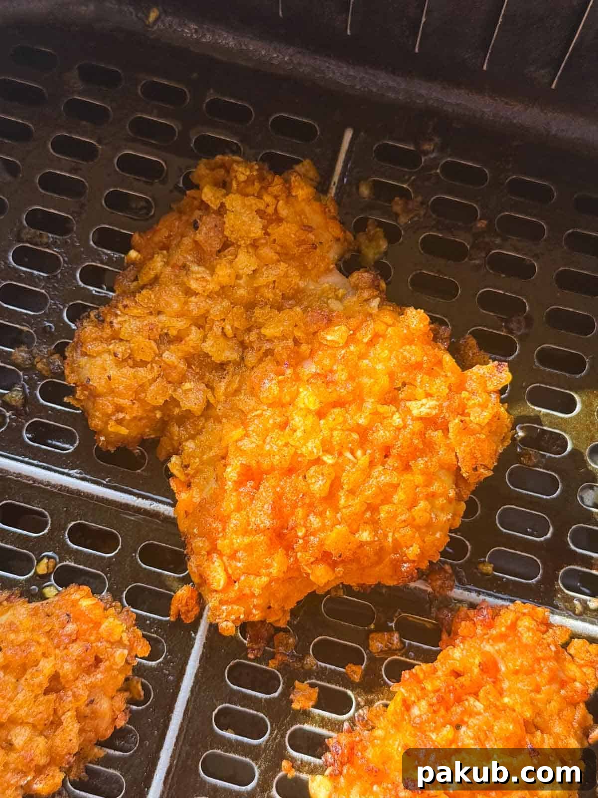 Marinated and perfectly breaded Nashville chicken pieces, meticulously arranged in an air fryer basket, eagerly awaiting their transformation into golden, crispy perfection.