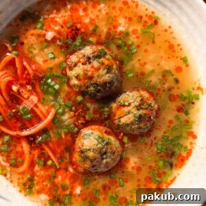Close-up of a serving of air fryer chicken meatballs in ginger broth, showcasing the textures and vibrant colors.