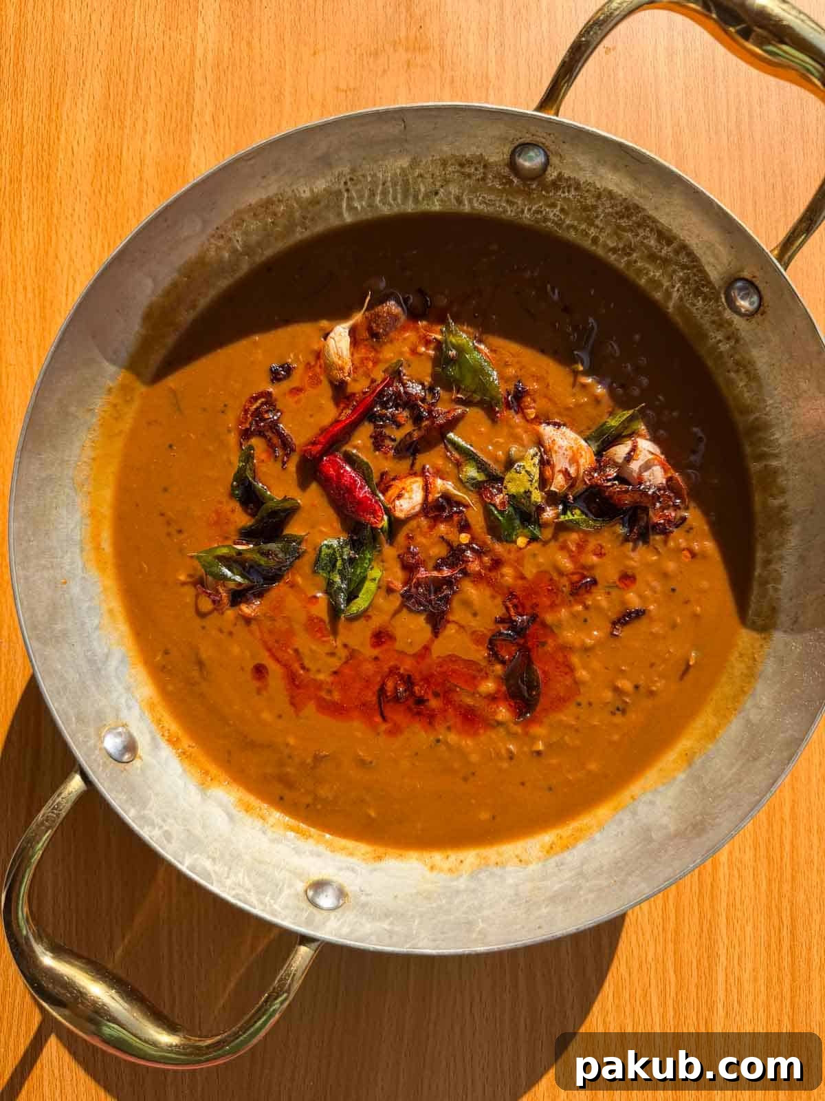 Freshly made horsegram dal in a traditional Indian kadai, garnished with tempering, ready to serve.