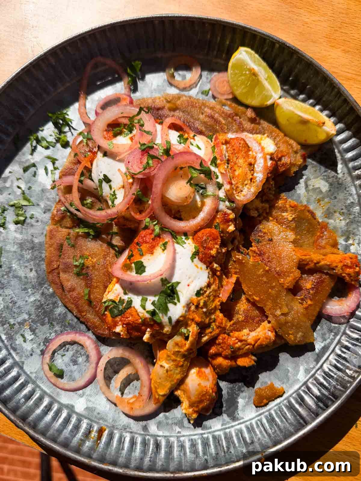 Iffa Chicken served on a plate with fresh accompaniments and a drizzle of creamy white sauce.
