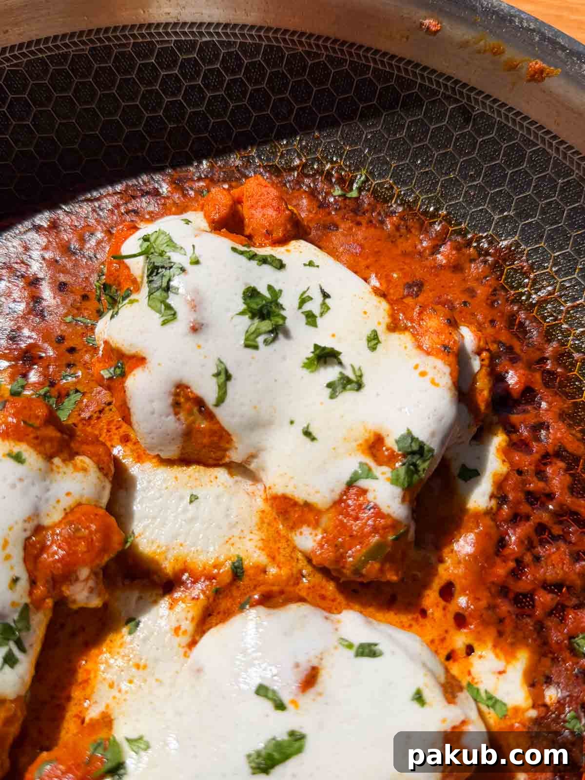 A close-up image of Iffa Chicken showing its inviting texture, golden-brown char, and creamy sauce drizzle.