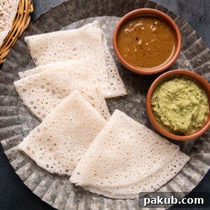 Delicate Neer Dosas served on a plate with fresh coconut chutney and a rich vegetable curry, highlighting their soft, lacy texture.