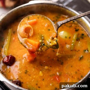 Delicious one-pot sambar, perfectly cooked and served with a ladle from the pressure cooker, showcasing its rich texture.