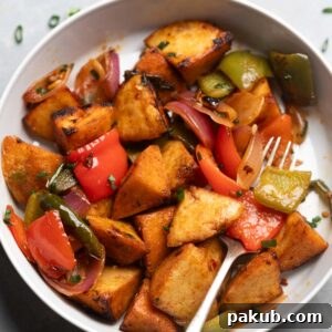 Freshly made chilli idli fry served in a white bowl with a fork, garnished with fresh curry leaves and chilies.