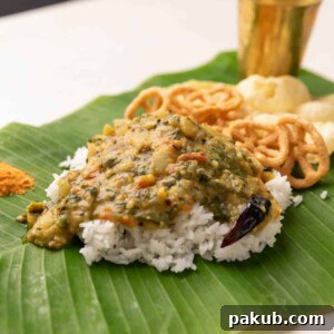 Steamed rice served on a banana leaf with Andhra Pappu, accompanied by crispy fryums and savory chutney podi, showcasing a traditional meal.