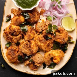Crispy Prawn Rava Fry served on a beige platter, accompanied by fresh chutney and thinly sliced onions, a perfect snack or appetizer.