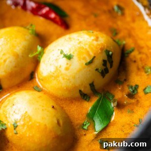 A close-up image of South Indian style egg curry, highlighting its creamy texture and perfectly boiled eggs, immersed in a rich, aromatic gravy.