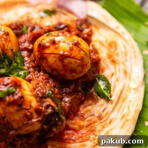 A close-up image of flavorful Kerala Egg Roast, served alongside flaky Malabar Parotta, a classic and comforting South Indian pairing.