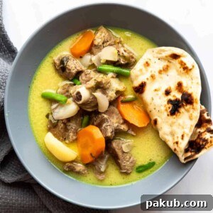 Creamy Mutton Stew with coconut, served in a inviting bowl alongside fluffy naan bread, a comforting and hearty meal.