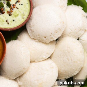 Soft and fluffy idlis, perfectly steamed, served with a side of vibrant coconut chutney, ready for a delightful South Indian breakfast.