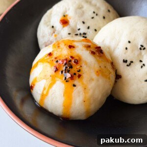 steamed buns or boazi served on a black plate with a drizzle of chilli oil