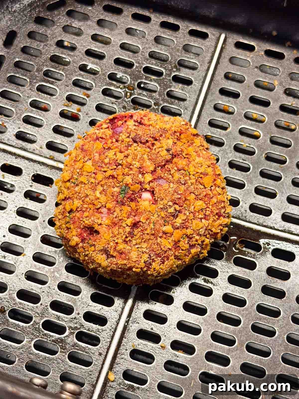 A close-up image of two perfectly air-fried Rajma Paneer tikkis resting in an air fryer basket, ready to be assembled into burgers.