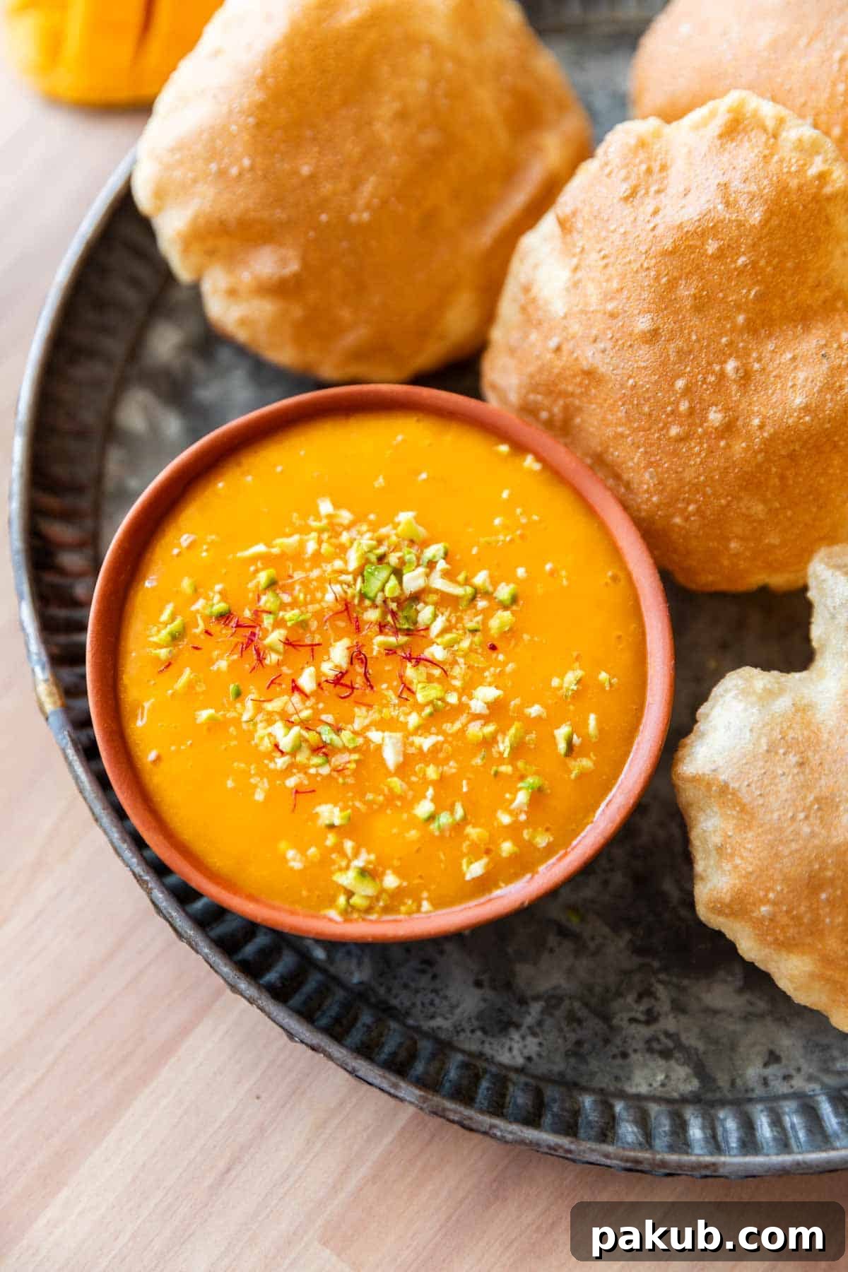 picture of aam ras on a plate with many puris