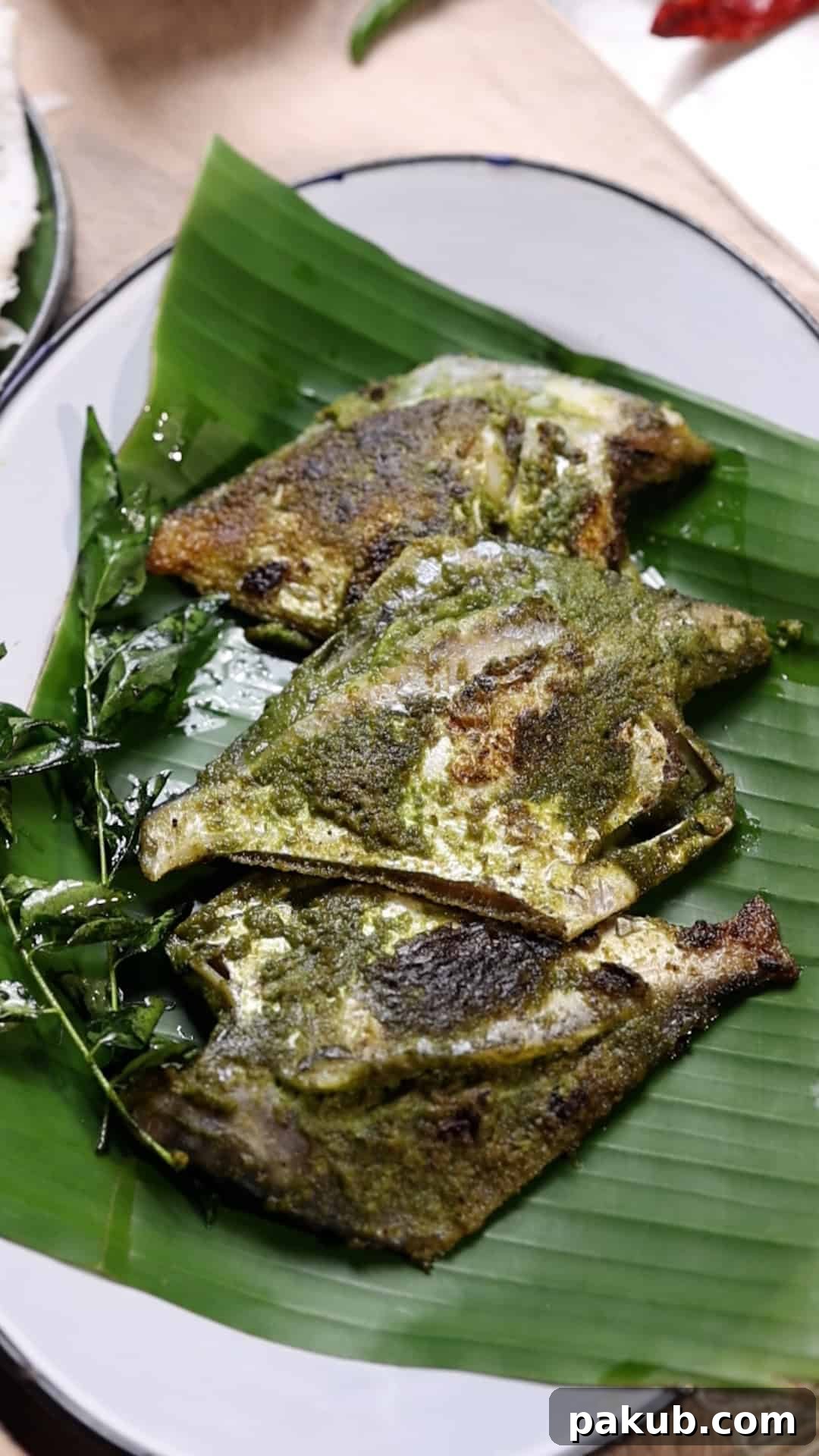 pomfret fry with green masala served on a plate of banana leaves