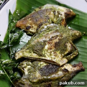 pomfret fry with green masala served on a plate of banana leaves