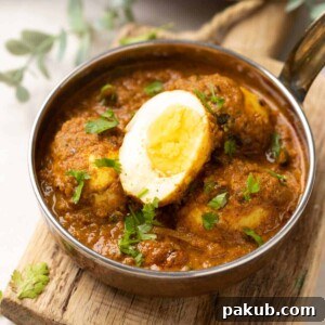 egg curry in steel bowl topped with coriander