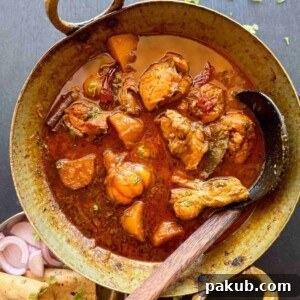 Bihari chicken curry served in a kadhai with roti and onions on the side